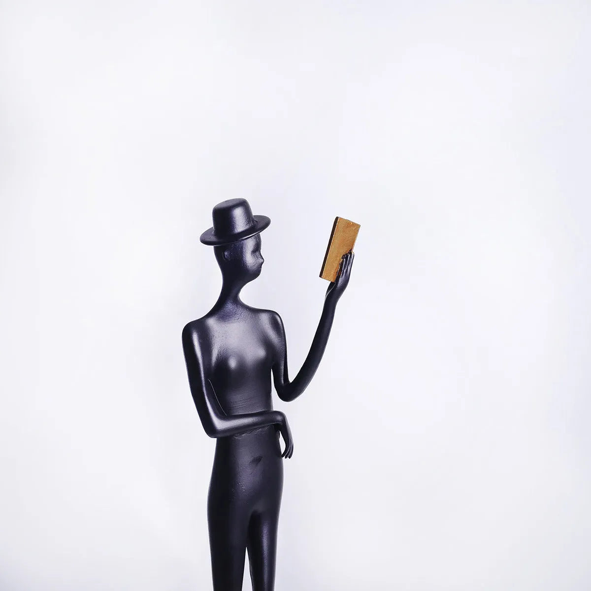 Black metal cast aluminium sculpture of reading woman on square base