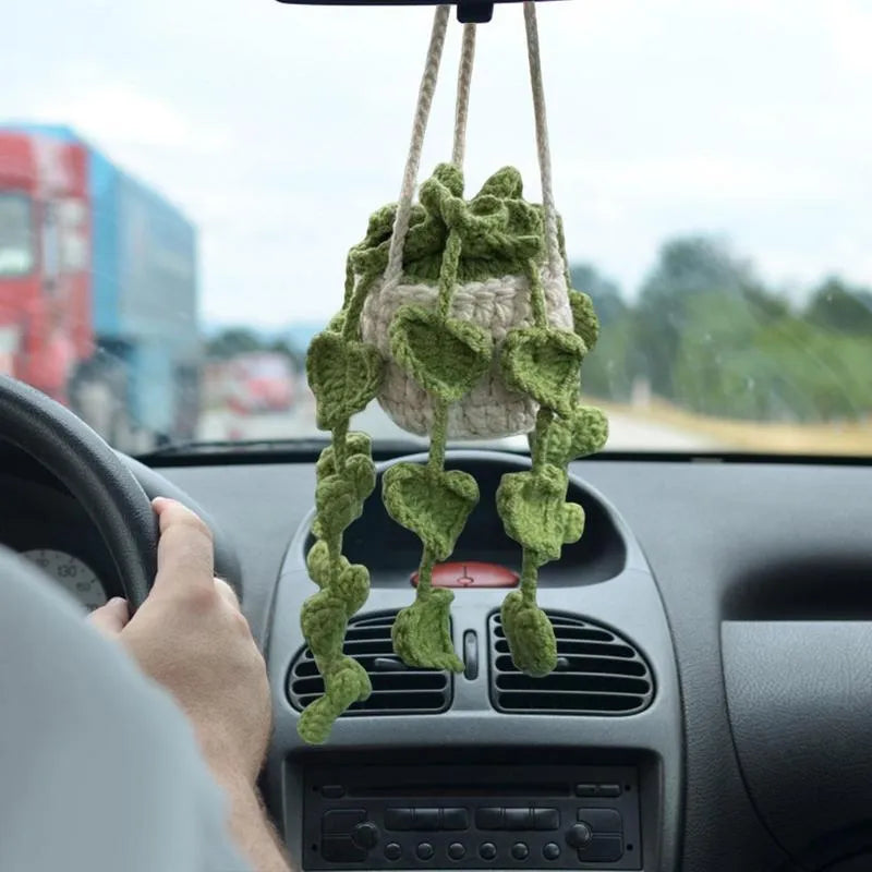 Green and white knitted wool car plant decoration with white hanging rope.
