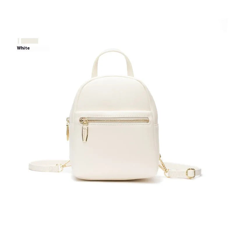 Soft black PU mini backpack with front pockets, shown open to reveal internal mobile phone sleeve and zipper compartment.
