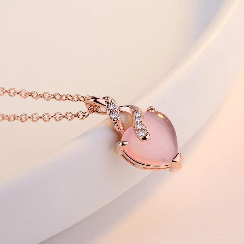 Rose gold heart-shaped pendant necklace with a pink synthetic crystal centre on a matching cross chain.