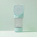 Green 3-in-1 portable pet water bottle with food container and waste bag dispenser, held by its hand strap.