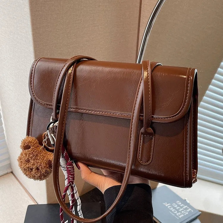 Women's brown PU leather square shoulder bag with pendant accessory showing interior zipper compartment