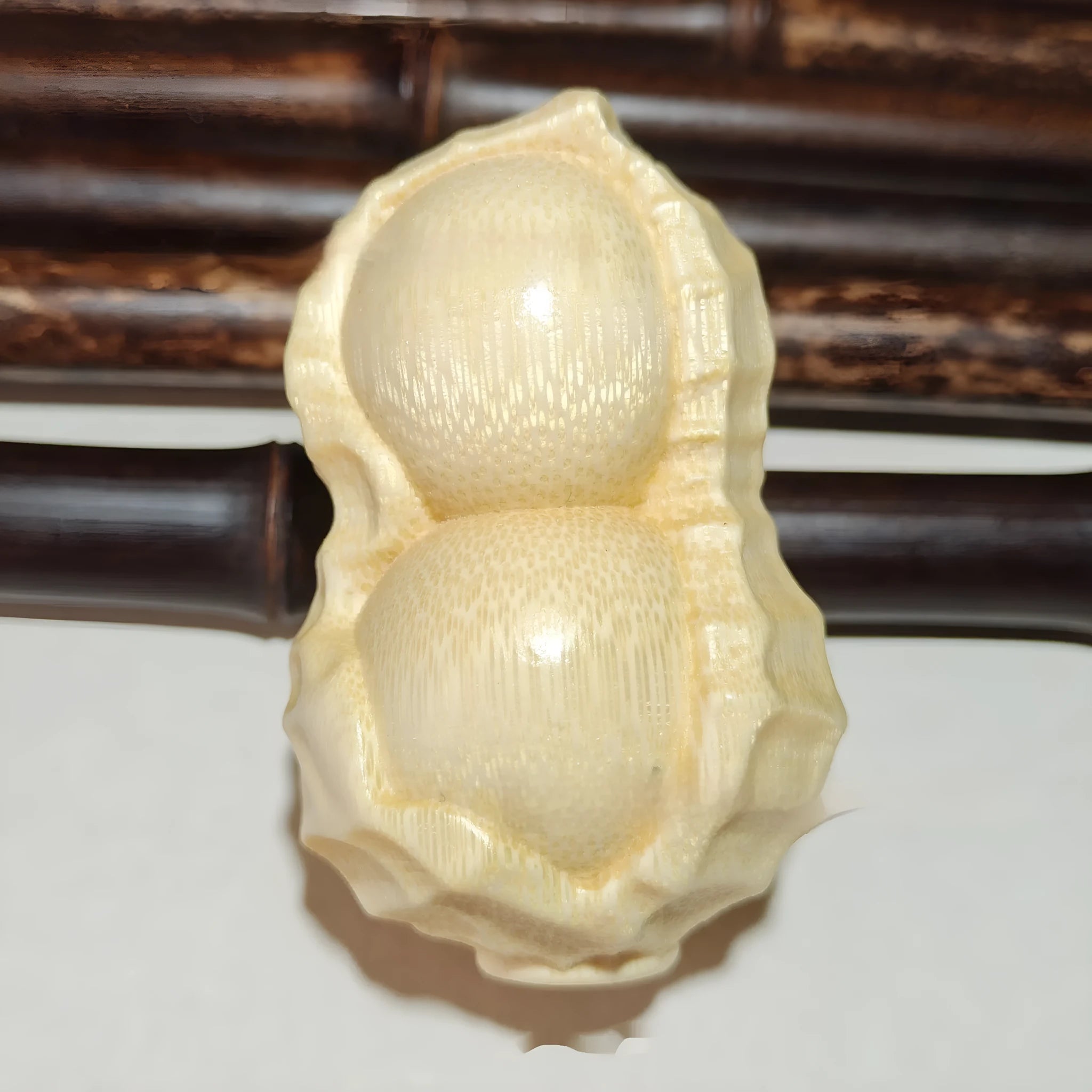 Carved solid bamboo peanut ornament in a modern simplicity style on a plain background.