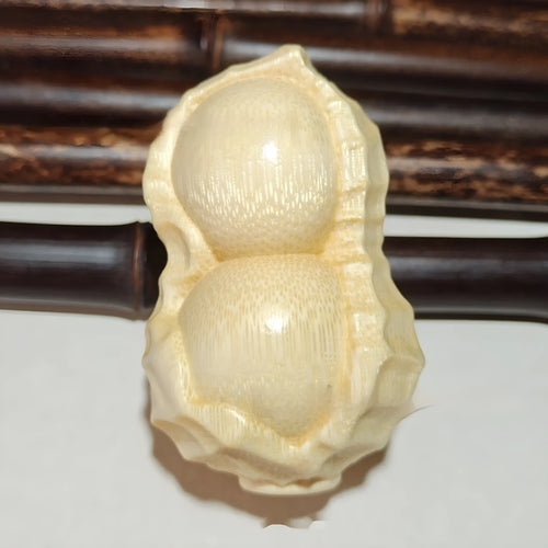 Carved solid bamboo peanut ornament in a modern simplicity style on a plain background.