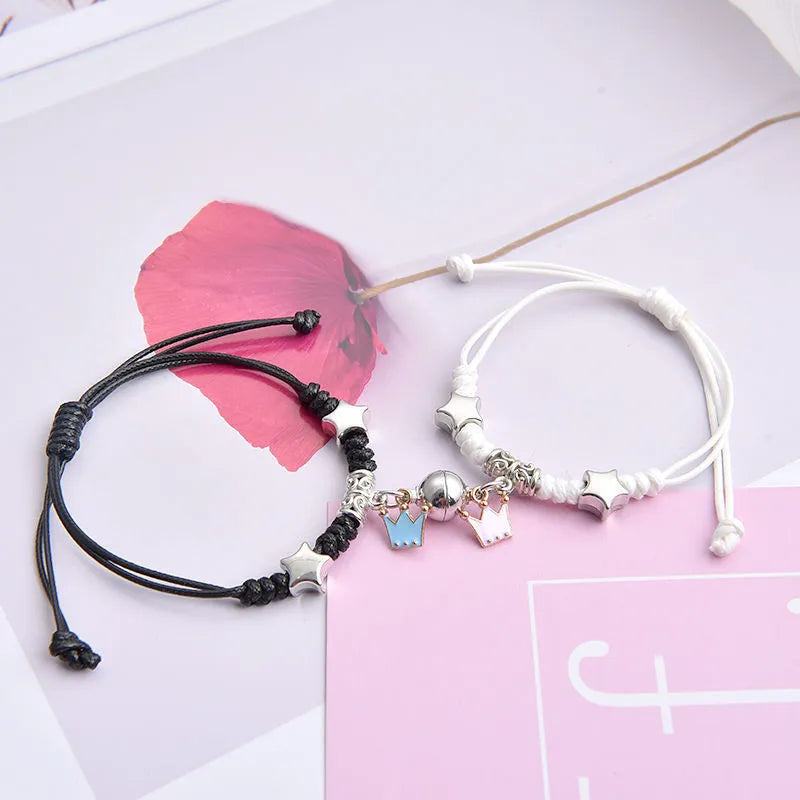 Pair of magnet couple bracelets with suction clasp on wrist, showing alloy designs like crown and love lock.