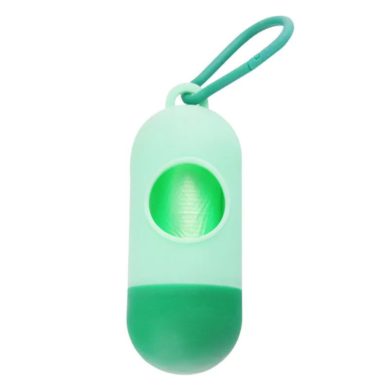 A small black plastic dog poop bag holder with a hook and Velcro strap, shown next to a roll of bags.