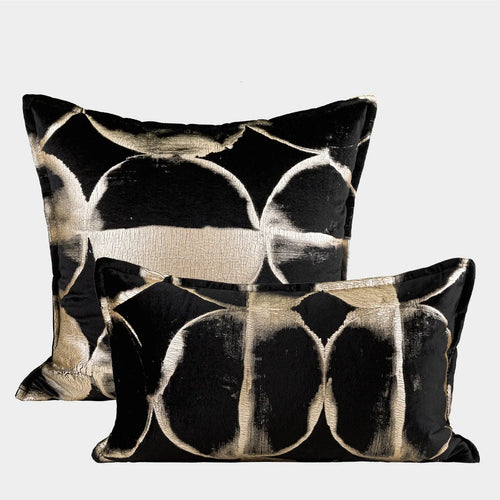 Black and gold abstract pattern flannel decorative cushion on a grey sofa.