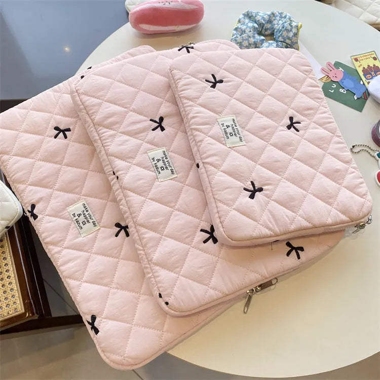 Cute white nylon laptop bag with a rhombus embroidered bow, shown next to a laptop.