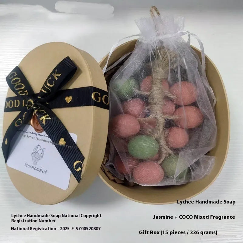 Handmade grape soap bars in black, green, and purple grape scents alongside litchi soap, with gift box and mesh bag packaging