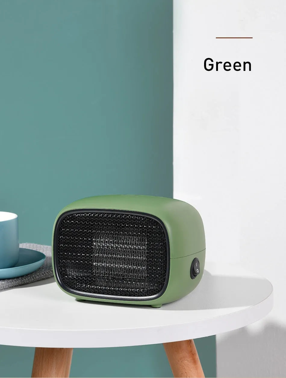 Compact green portable ceramic fan heater with metal grille, shown on a desk