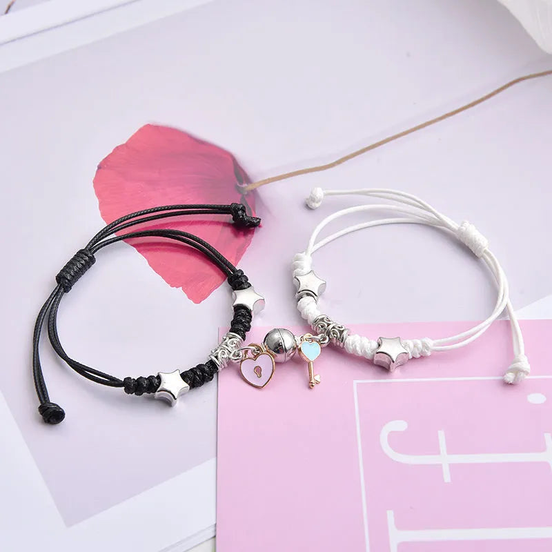 Pair of magnet couple bracelets with suction clasp on wrist, showing alloy designs like crown and love lock.