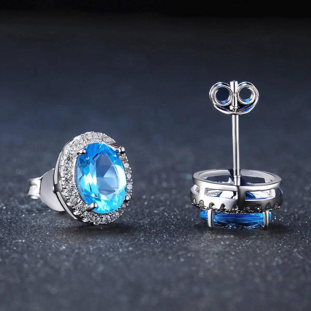Women's 925 sterling silver jewellery set with blue topaz gemstones showing earrings, ring, pendant, and necklace with geometric pattern