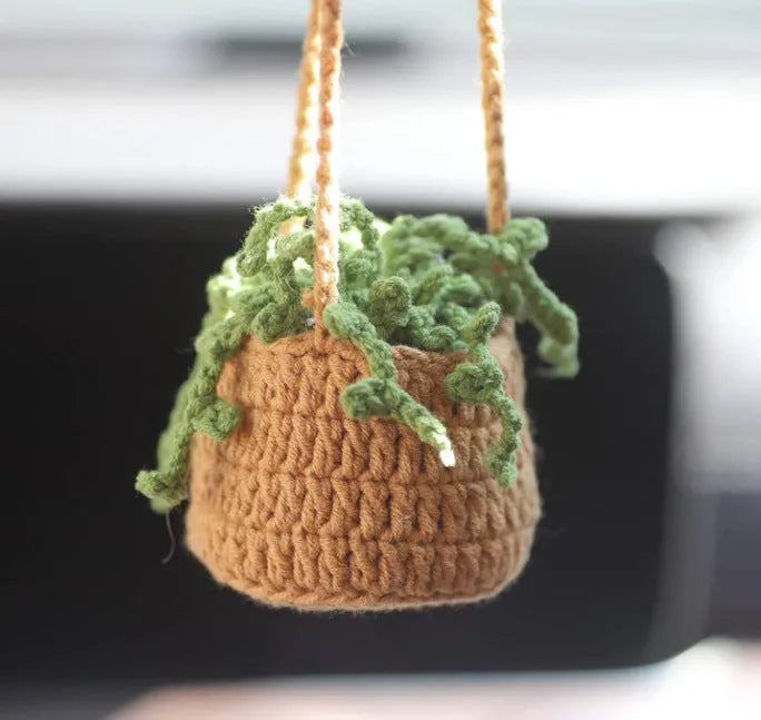 Green and white knitted wool car plant decoration with white hanging rope.