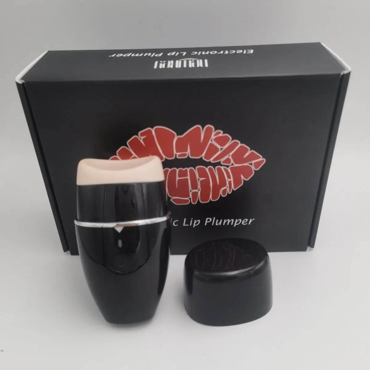 Black electric lip plumper device with a silicone tip next to a white USB charging cable.