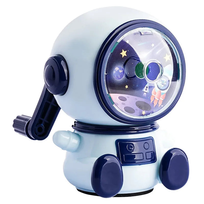 Blue and pink cartoon astronaut model manual pencil sharpener for children on a desk.