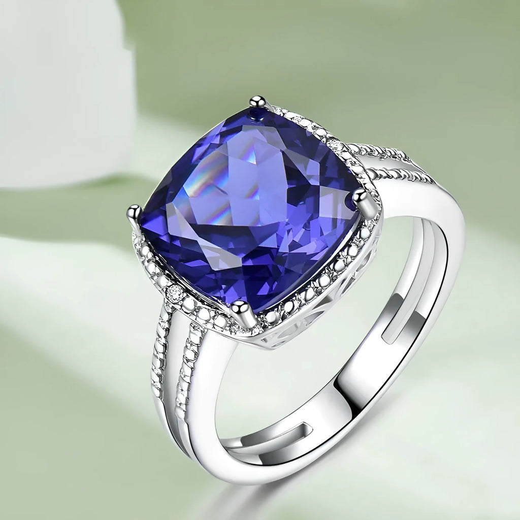 Blue tanzanite stone set in a sterling silver women's ring on a finger.