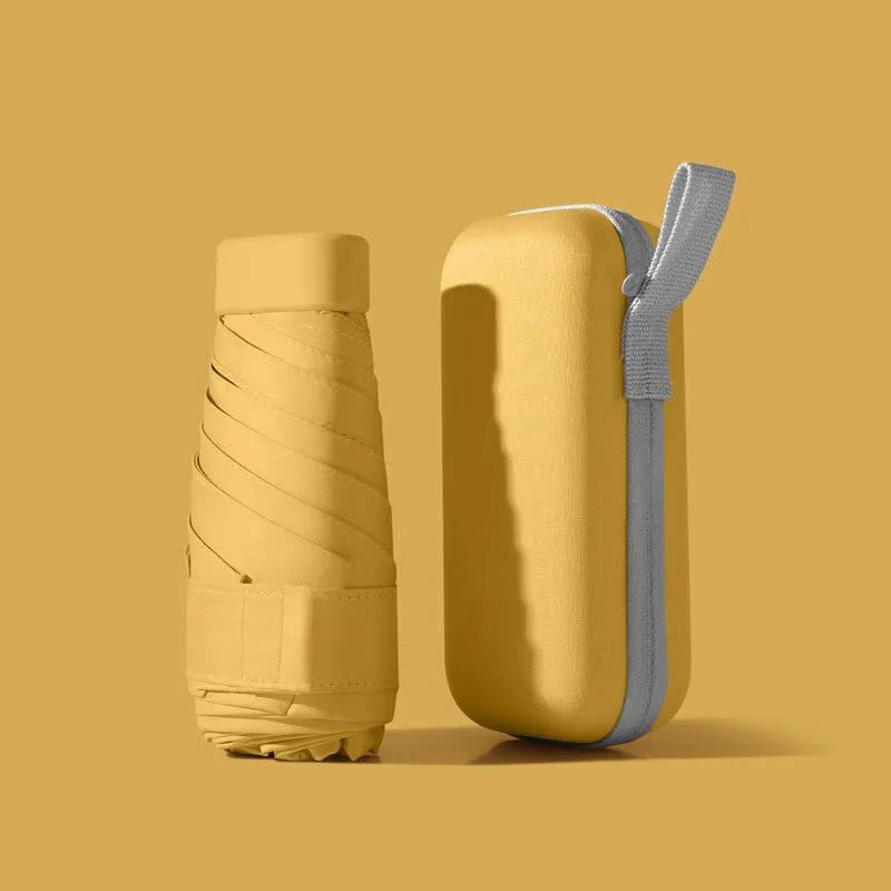 A folded six-fold flat umbrella in a capsule box, showing the steel ribs and rubber handle.