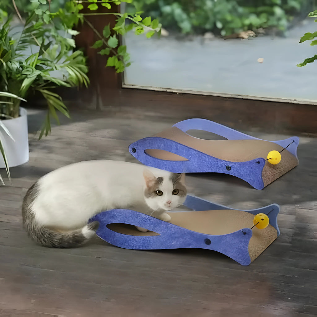Blue fish-shaped cardboard cat scratcher lounger with a red bell ball toy on an elastic cord.