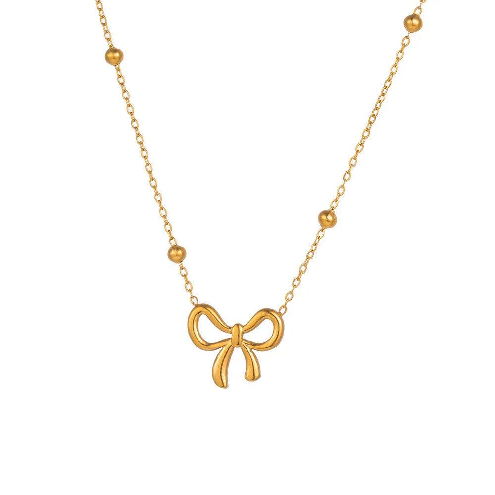 Gold electroplated bow necklace with adjustable chain on white background