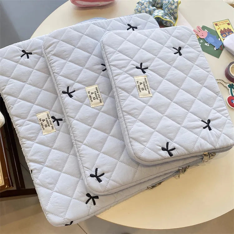 Cute white nylon laptop bag with a rhombus embroidered bow, shown next to a laptop.