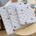 Cute white nylon laptop bag with a rhombus embroidered bow, shown next to a laptop.