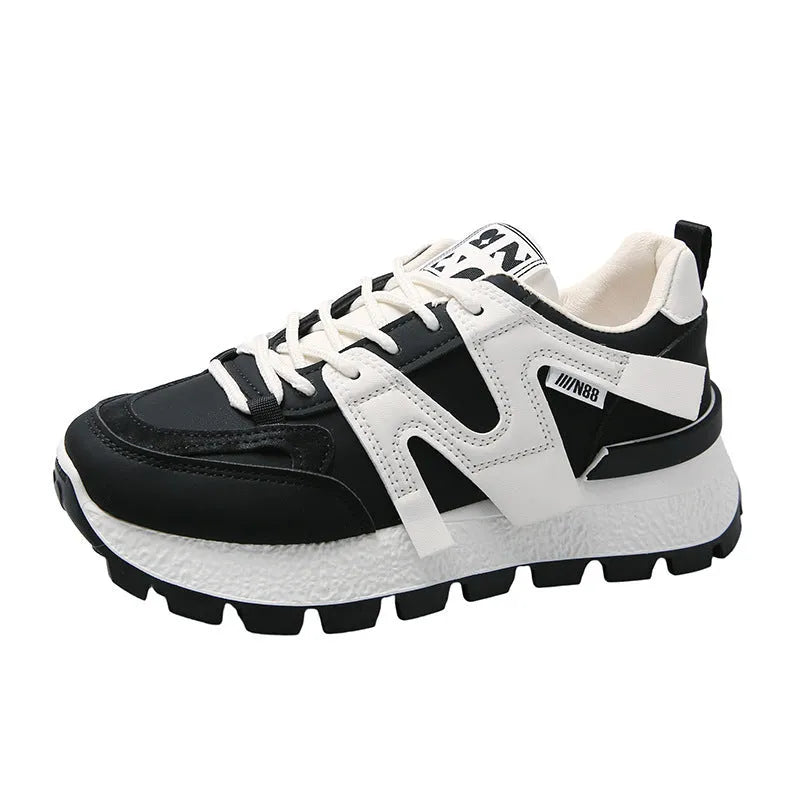 A pair of low-top black or white sneakers with a round toe, lace-up front, and flat rubber sole.