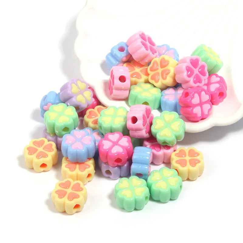 A pile of 15mm frosted acrylic four-leaf clover beads in mixed colours including pink, green, and blue.