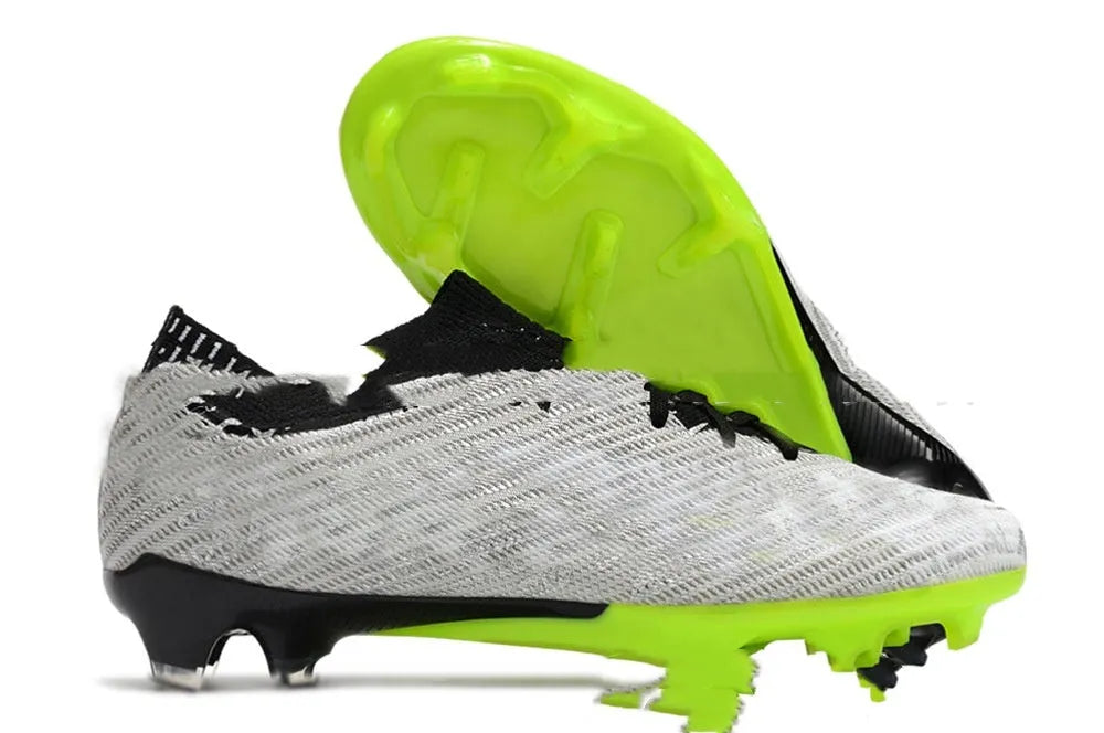 Men's black football shoes with FG studs, knitted upper, and lace-up closure on grass pitch