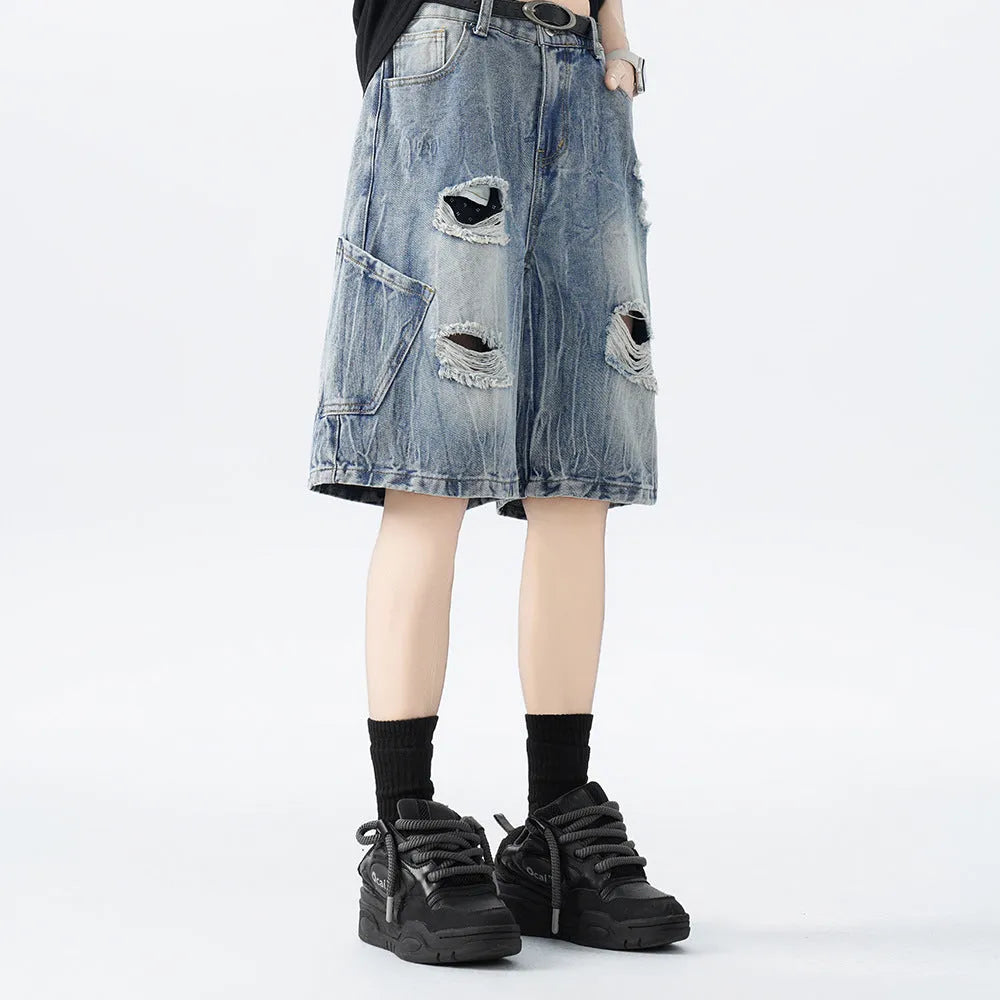 Man's loose-fit ripped denim shorts in washed black showing distressed details and retro styling