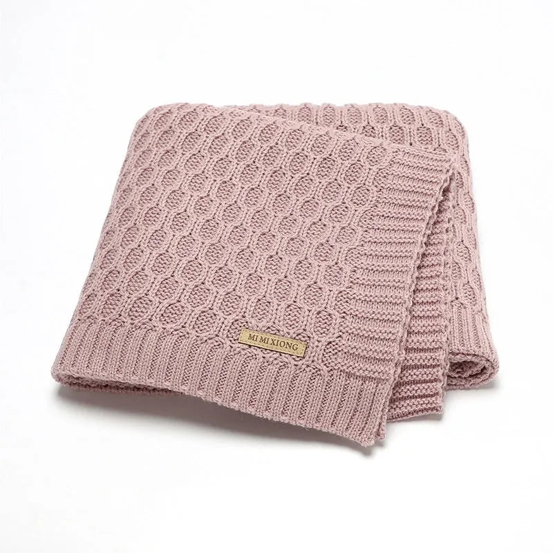 Solid colour infant hug blanket with three-dimensional line texture, shown in a choice of colours.