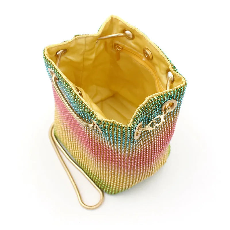 Colourful rhinestone fabric bucket bag with a sparkling jewelled shoulder strap on a white background