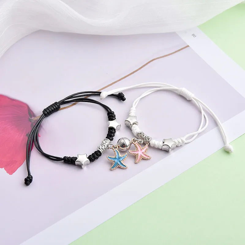 Pair of magnet couple bracelets with suction clasp on wrist, showing alloy designs like crown and love lock.
