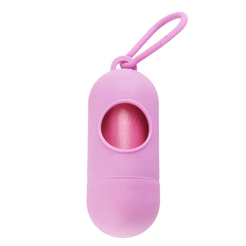 A small black plastic dog poop bag holder with a hook and Velcro strap, shown next to a roll of bags.