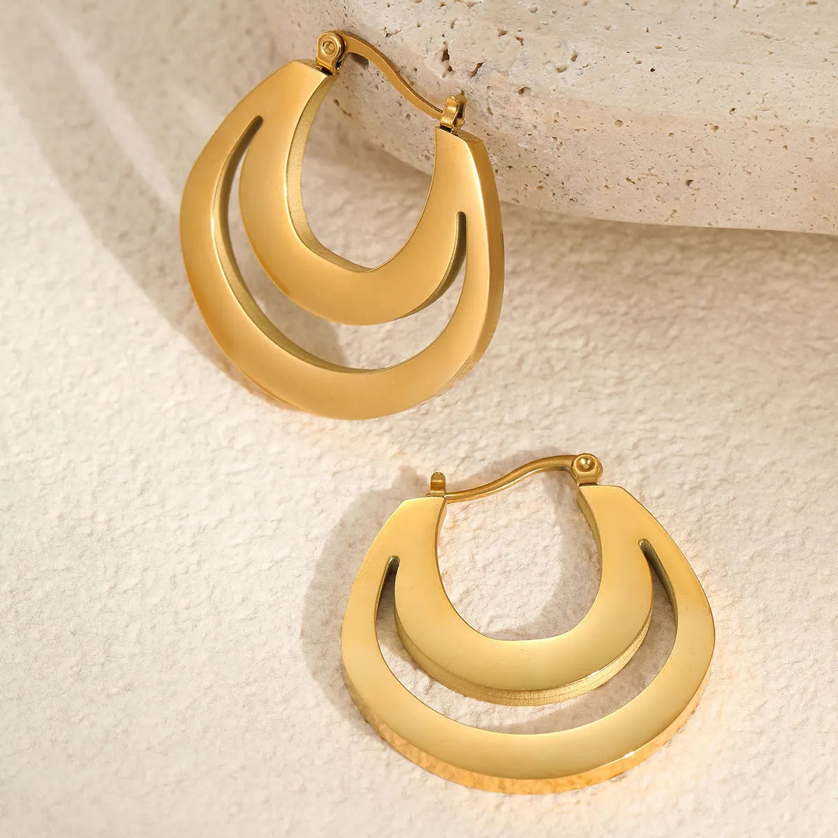 Geometric gold plated hoop earrings with round ring design on stainless steel background