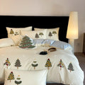Four-piece cotton bedding set with Christmas tree towel embroidery pattern showing duvet cover, bed sheet, and pillowcases