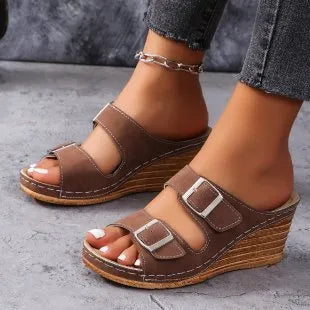 Women's creamy-white beach slippers with an outer wedge belt buckle on a flat rubber sole.