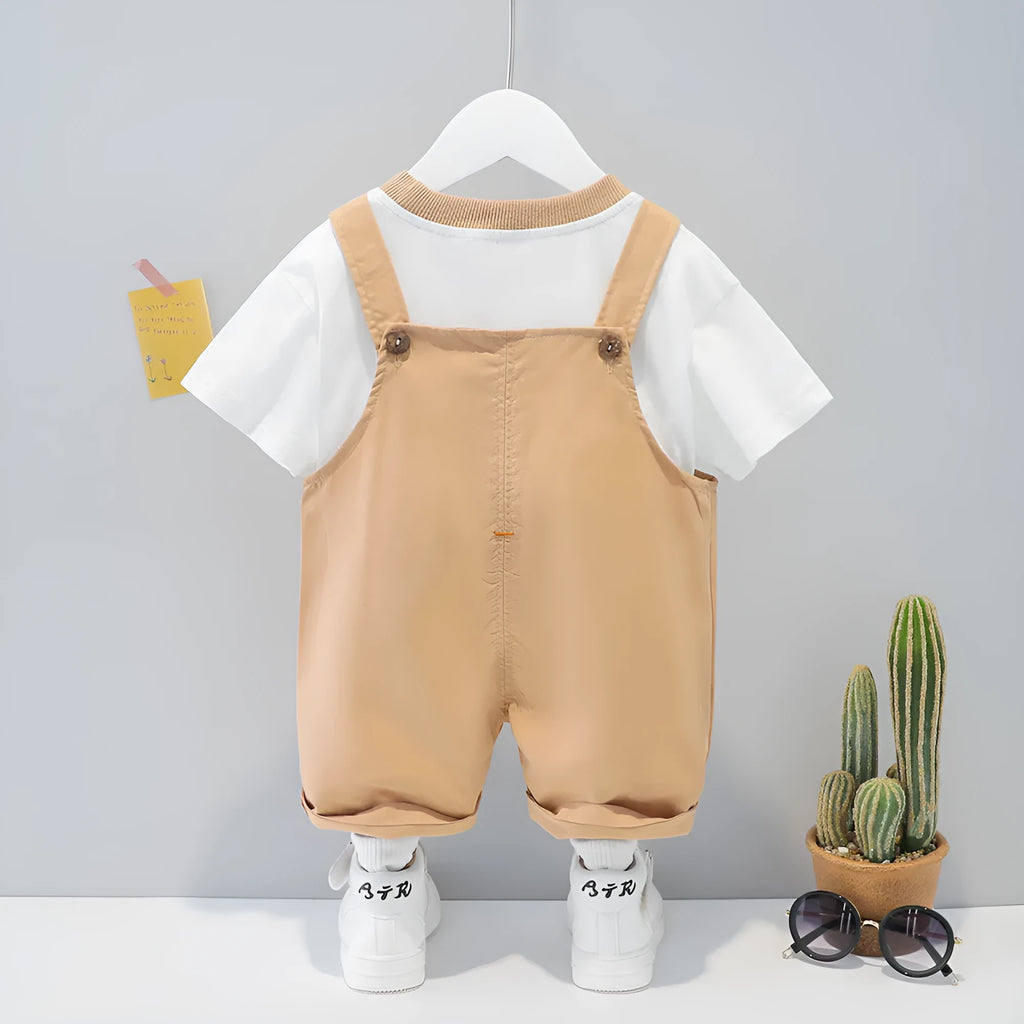 Yellow cotton baby romper with cartoon print and openable shoulder straps, laid flat.