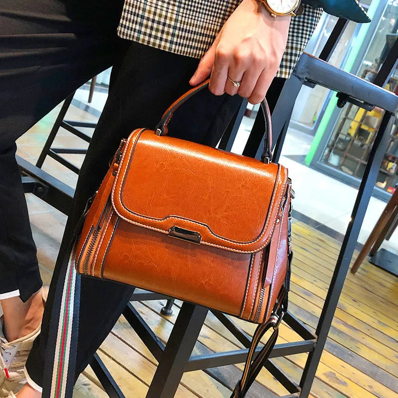 Women's brown genuine oil wax leather messenger bag with double strap and external pocket.