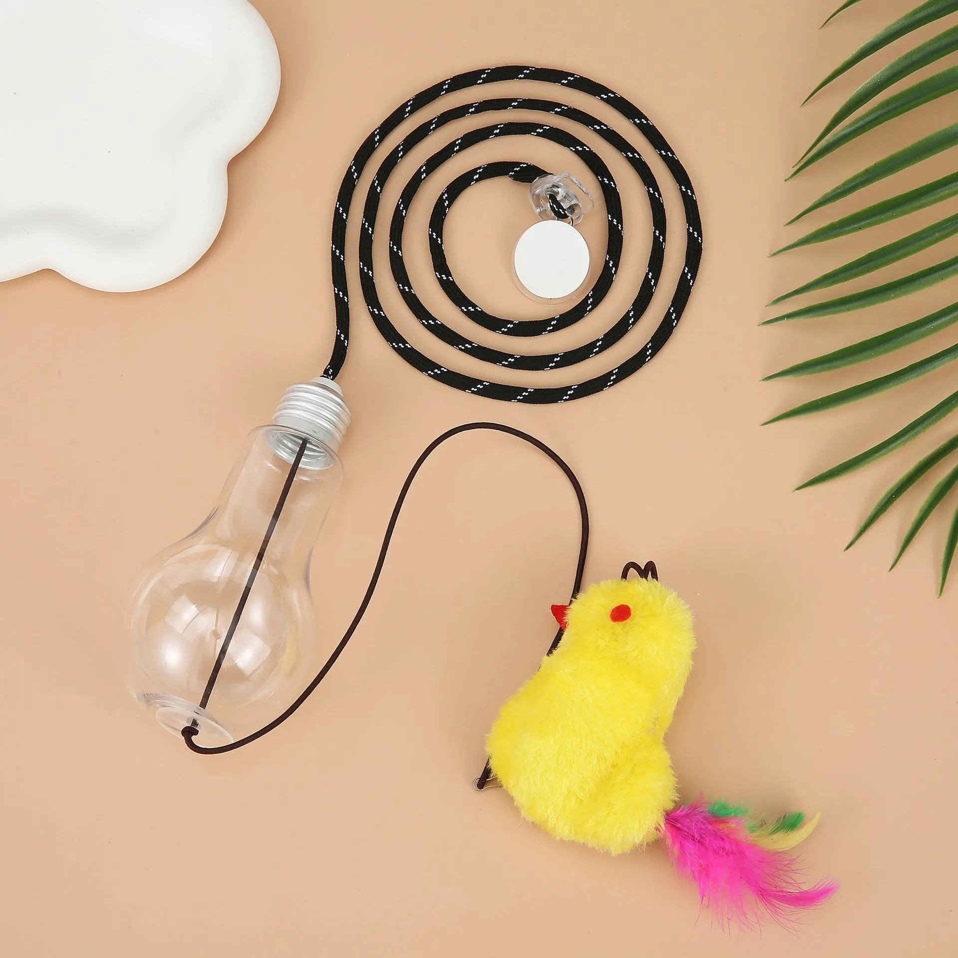 Gray and yellow hanging interactive cat toy with treat dispenser extended on elastic rope