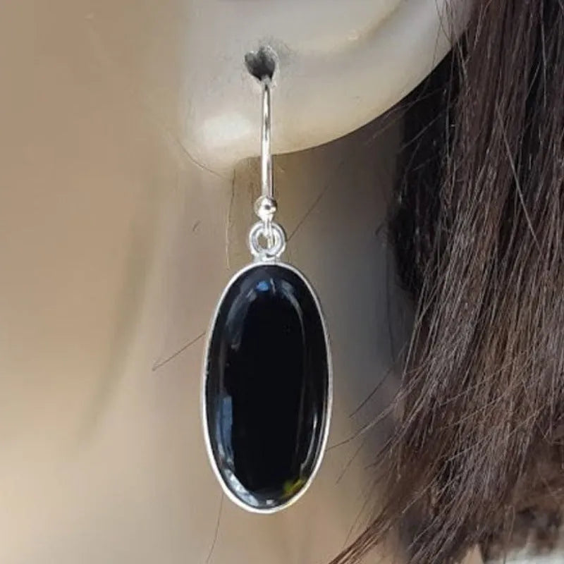 Pair of women's earrings with oval black agate pendant on silver electroplated alloy geometric setting.