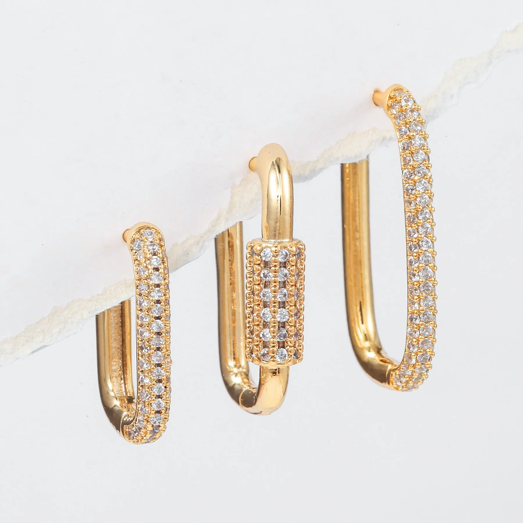 Three geometric copper earrings with zircon micro inlay in clip-on design showing ellipse and quadrilateral shapes
