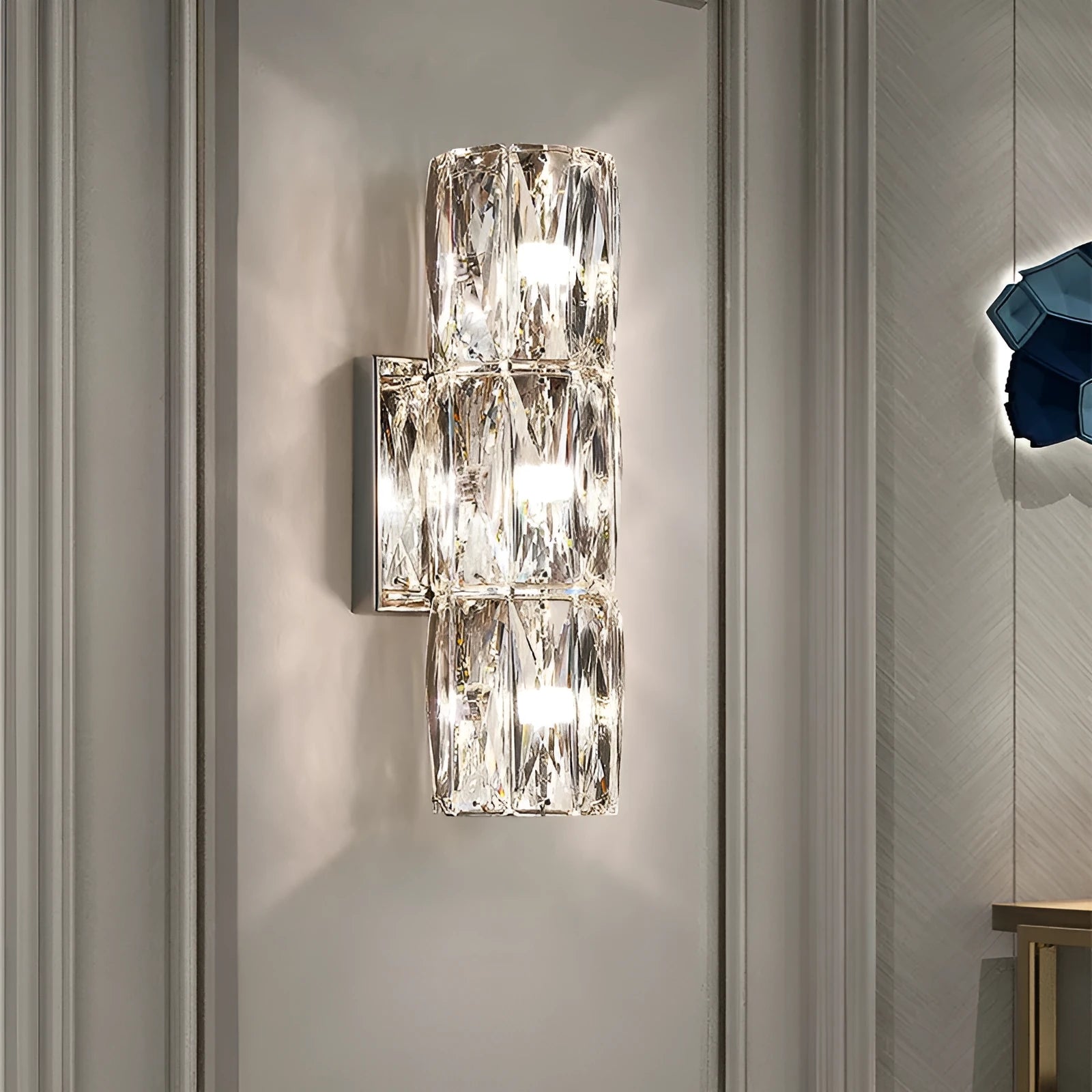 Crystal wall lamp with stainless steel frame in gold or chrome finish, mounted on a wall.