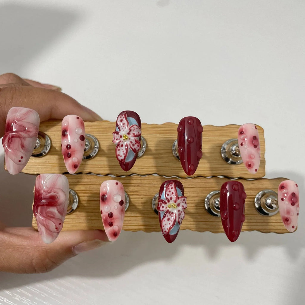 Almond-coloured false nails with hand-painted 3D carved rose designs, shown in medium length.
