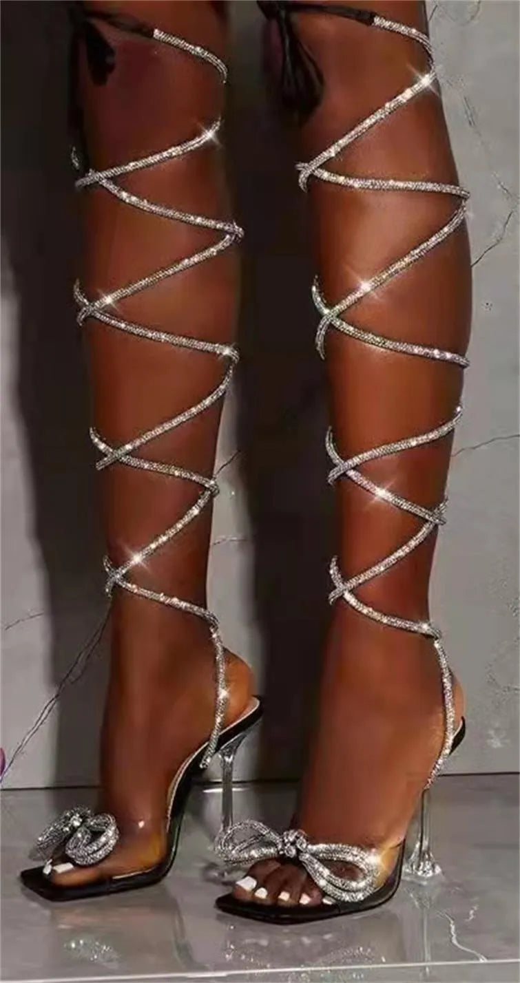 Plus size women's strappy sandal with rhinestone Roman ankle straps and a square toe, shown in black.