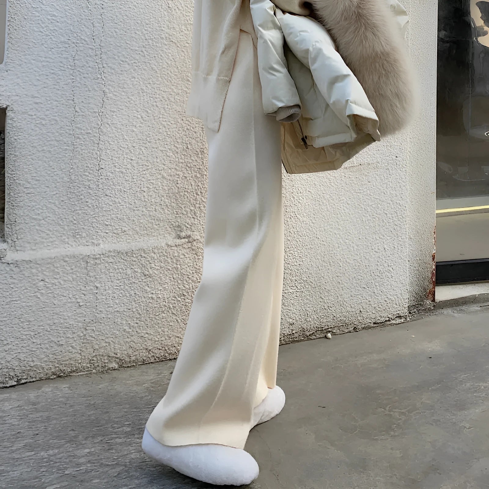 Women's high waist wide-leg knit trousers in cream white colour, laid flat to show straight-leg cut.