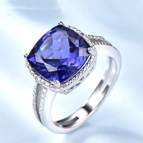 Blue tanzanite stone set in a sterling silver women's ring on a finger.