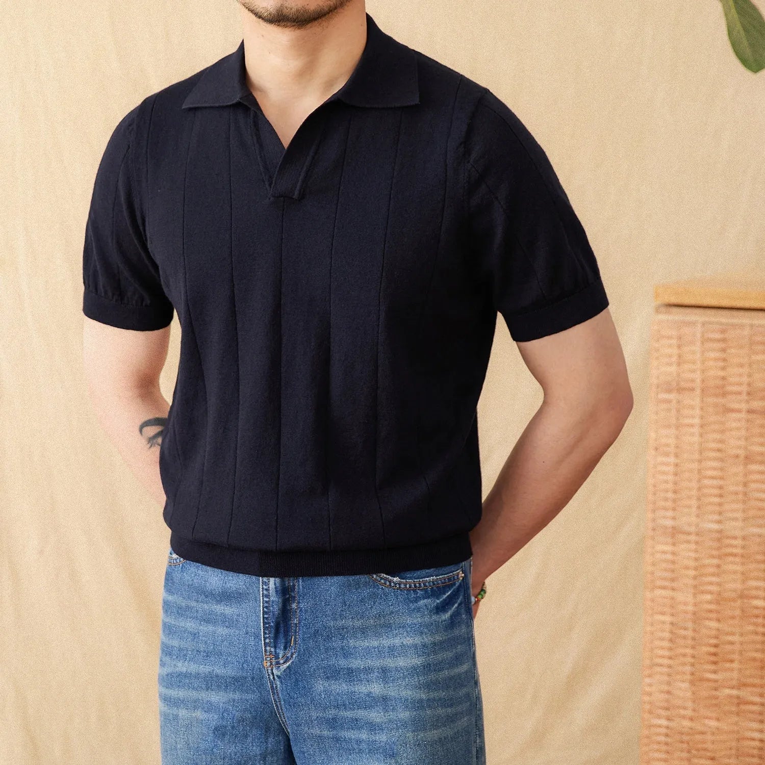 Man modelling a purple short sleeve polo shirt with a sunken stripe knit pattern and a seagull collar.
