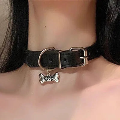 Black adjustable dog collar with small bell charm shown in leather, bone, and cat's paw designs.