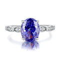Heart shaped Tanzanite purple zircon ring in sterling silver on a grey background.