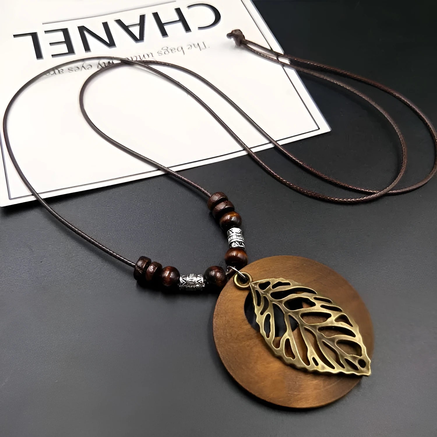 Wooden pendant necklace with alloy leaf details on a brown adjustable wax line chain.